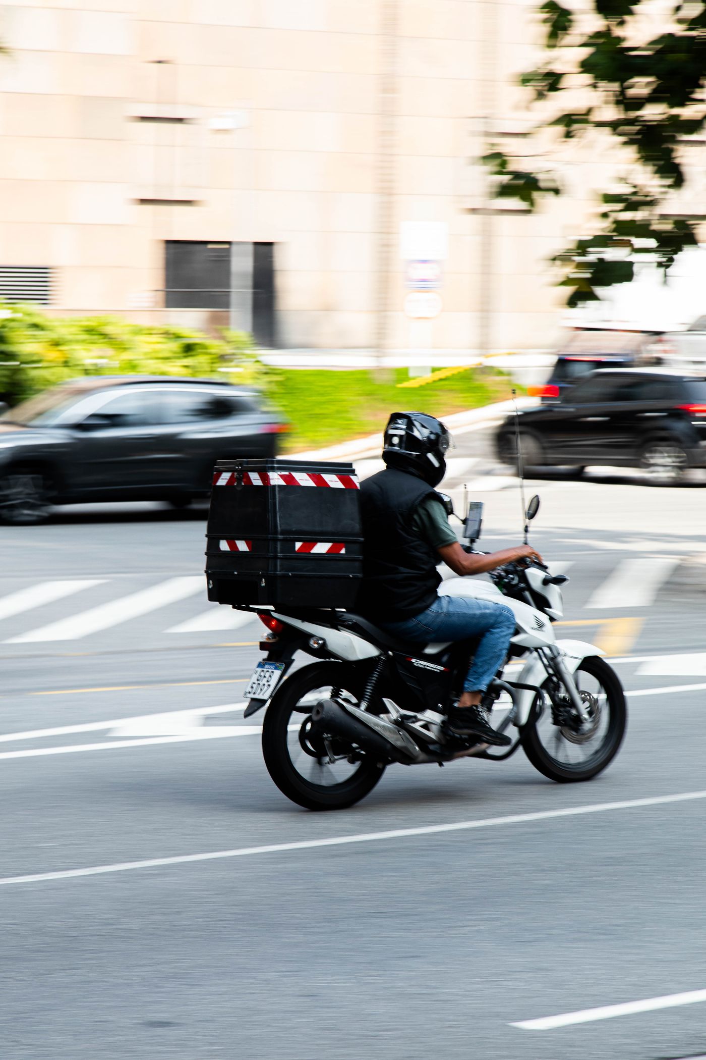 Motoboy com bau de entregas em avenida