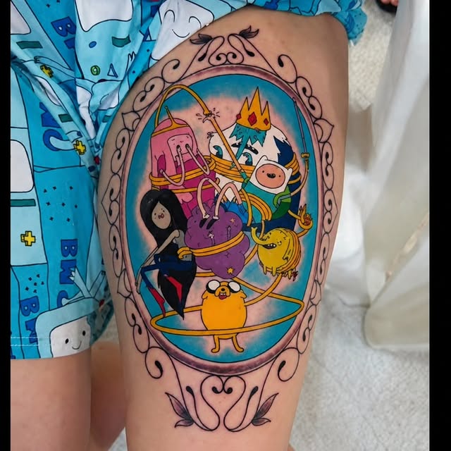 Tatuagem colorida autoral na coxa, com moldura desenhada